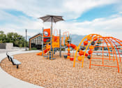 Thumbnail 23 of 26 - A playground with orange and black equipment and a brown bench.