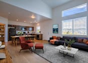 Thumbnail 2 of 21 - A modern living room with a kitchen area in the background.