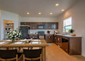 Thumbnail 1 of 21 - A kitchen with a table set for two with a vase of flowers on it.
