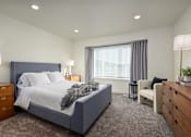 Thumbnail 8 of 26 - A bedroom with a large bed, a chair, and a nightstand.