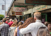 Thumbnail 14 of 18 - a crowd of people walking down a sidewalk in front of a building with a sign that says