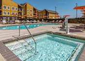 Thumbnail 20 of 34 - A swimming pool in front of a building with orange umbrellas.