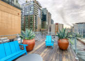 Thumbnail 7 of 18 - a rooftop deck with two blue chairs and two large succulents