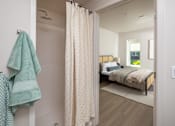 Thumbnail 12 of 34 - A bathroom with a towel hanging on the wall and a bed in the background.