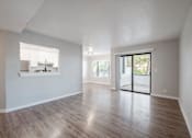 Thumbnail 25 of 27 - A spacious room with wooden flooring and a sliding glass door leading to a balcony.