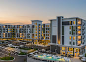 Thumbnail 7 of 28 - A large hotel building with a pool in front.