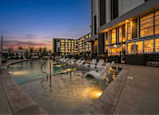 Thumbnail 5 of 28 - A pool with chairs around it is lit up at dusk.
