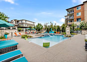 Thumbnail 10 of 28 - A swimming pool surrounded by a patio with chairs and umbrellas.