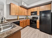 Thumbnail 3 of 25 - A kitchen with black appliances and wooden cabinets.