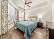 Thumbnail 10 of 25 - A bedroom with a bed, nightstand, and a ceiling fan.