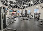Thumbnail 16 of 25 - A gym with a variety of equipment including a punching bag.