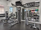 Thumbnail 17 of 25 - A gym with a variety of equipment including a leg press machine, a chest press machine, and a squat rack.