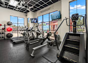 Thumbnail 18 of 25 - A gym with a treadmill, exercise bike, and other equipment.