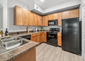 Thumbnail 2 of 12 - A kitchen with black appliances and wooden cabinets.