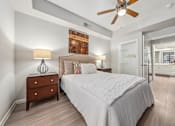 Thumbnail 3 of 12 - A bedroom with a large bed, a wooden dresser, and a ceiling fan.