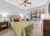 Thumbnail 4 of 12 - A bedroom with a bed, nightstand, and a ceiling fan.