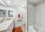 Thumbnail 5 of 12 - A white bathroom with a white tub and a white sink.