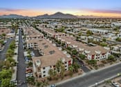 Thumbnail 12 of 12 - A sunset view of a residential area with apartment buildings and cars parked in the driveways.