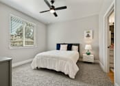 Thumbnail 21 of 42 - A bedroom with a white bed and a ceiling fan.