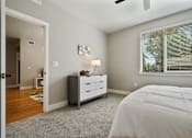 Thumbnail 23 of 42 - A bedroom with a white bed, a grey dresser, and a window with blinds.