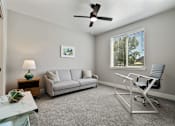 Thumbnail 25 of 42 - A living room with a grey couch, a white chair, and a green lamp.