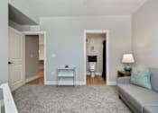 Thumbnail 27 of 42 - A living room with a grey couch and a grey rug.