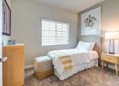 Thumbnail 17 of 18 - A bedroom with a bed, nightstand, and lamp.