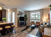 Thumbnail 3 of 26 - A modern living room with a bar area and a large window.