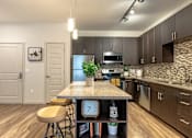 Thumbnail 2 of 26 - A kitchen with a granite countertop and wooden floors.