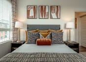 Thumbnail 5 of 26 - A bedroom with a bed, two lamps, and three framed artworks on the wall.