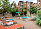 Thumbnail 8 of 26 - A pool area with sun loungers and umbrellas in front of a building.
