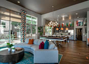 Thumbnail 12 of 26 - A modern living room with a curved sofa and a round coffee table.