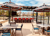 Thumbnail 14 of 15 - A patio with tables and chairs under striped umbrellas.