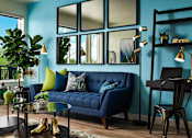 Thumbnail 10 of 15 - A living room with a blue couch, a glass table, and a mirror on the wall.