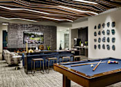 Thumbnail 11 of 15 - A pool table is in the middle of a room with a bar and a picture on the wall.
