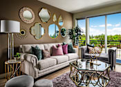 Thumbnail 3 of 15 - A living room with a white couch, a glass table, and a purple rug.