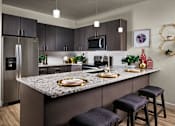 Thumbnail 1 of 15 - A modern kitchen with a granite countertop and dark brown cabinets.