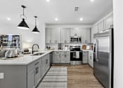 Thumbnail 3 of 28 - A modern kitchen with a refrigerator, sink, and cabinets.