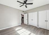 Thumbnail 22 of 33 - A room with a ceiling fan and three white doors.