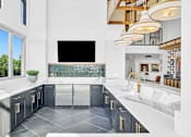 Thumbnail 15 of 28 - A modern kitchen with a large island and a flat screen TV mounted on the wall.