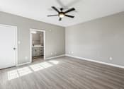 Thumbnail 19 of 33 - A room with a ceiling fan and light, hardwood floors, and a white door.