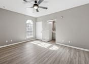 Thumbnail 21 of 33 - A room with a ceiling fan and wooden flooring.