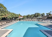 Thumbnail 7 of 39 - A large outdoor swimming pool surrounded by lounge chairs and trees.