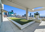 Thumbnail 13 of 41 - A rooftop patio with a white column and a green lawn.