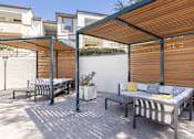 Thumbnail 4 of 33 - A patio with a striped couch and a table with a potted plant on it.