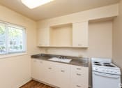 Thumbnail 54 of 55 - A small kitchen with white cabinets and a stove.