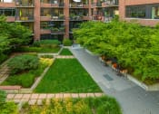 Thumbnail 30 of 44 - Aerial view of a courtyard with a grassy area and a brick building in the background at The Wyatt, Portland, OR, 97209
