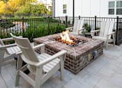 Thumbnail 26 of 27 - A fire pit with a fire burning in it surrounded by chairs.
