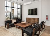 Thumbnail 20 of 27 - A modern living room with a wooden coffee table and black leather chairs.