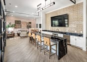 Thumbnail 11 of 27 - A kitchen with a bar area and a television mounted on the wall.